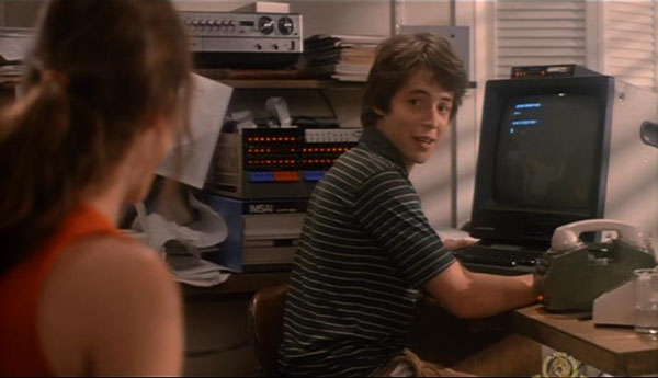 Still from the movie WarGames: David Lightman sits at an early home computer with a telephone modem, glancing over his shoulder.