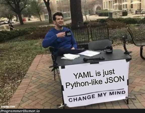 'Change My Mind' meme: a man seated at a table behind a sign that reads 'YAML is just Python-like JSON.'